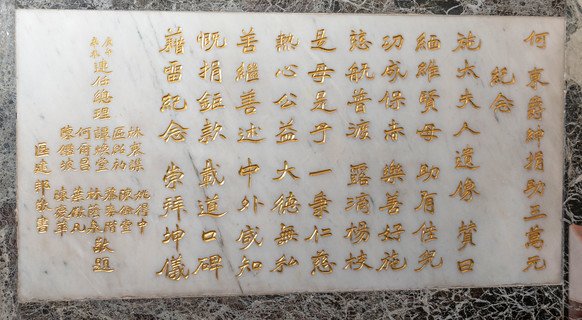 刻於何東太夫人（施太夫人）畫像之下的碑文的書法，同樣出自多次為本局揮毫的書法家區建公。